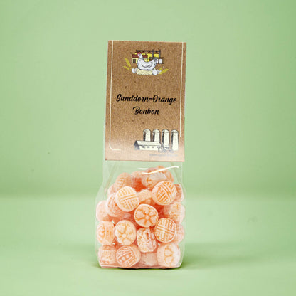 Frontalansicht von Sanddorn-Orange Bonbons in einer transparenten Plastiktüte mit einem Pappetikett.