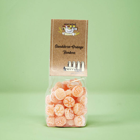 Frontalansicht von Sanddorn-Orange Bonbons in einer transparenten Plastiktüte mit einem Pappetikett.