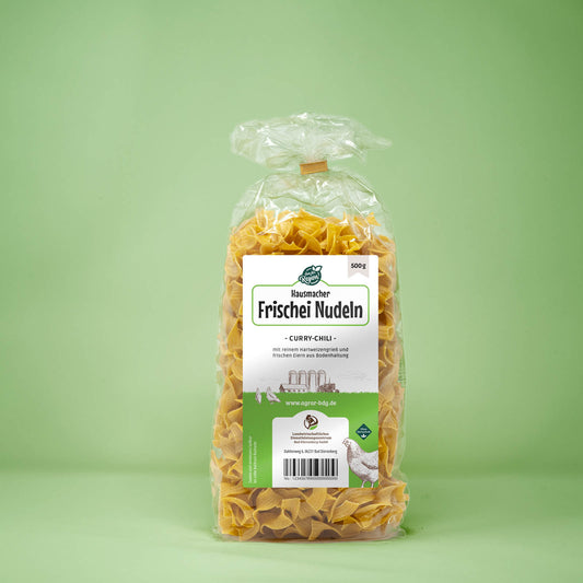 Frontalansicht von Hausmacher Frischei Curry-Chilli Nudeln 500 Gramm in einer Plastiktüte mit Etikett.