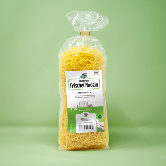 Frontalansicht von Hausmacher Frischei Fadennudeln 250 Gramm in einer Plastiktüte mit Etikett.