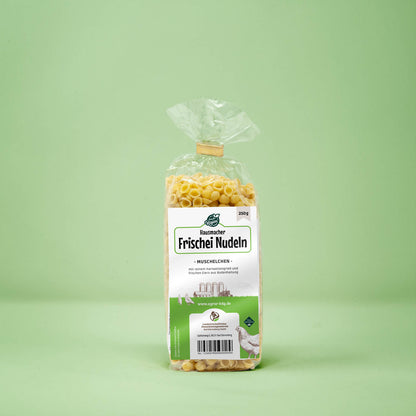 Frontalansicht von Hausmacher Frischei Muschelchen Nudeln 250 Gramm in einer Plastiktüte mit Etikett.