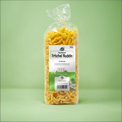 Frontalansicht von Hausmacher Frischei Spiralen Nudeln 500 Gramm in einer Plastiktüte mit Etikett.