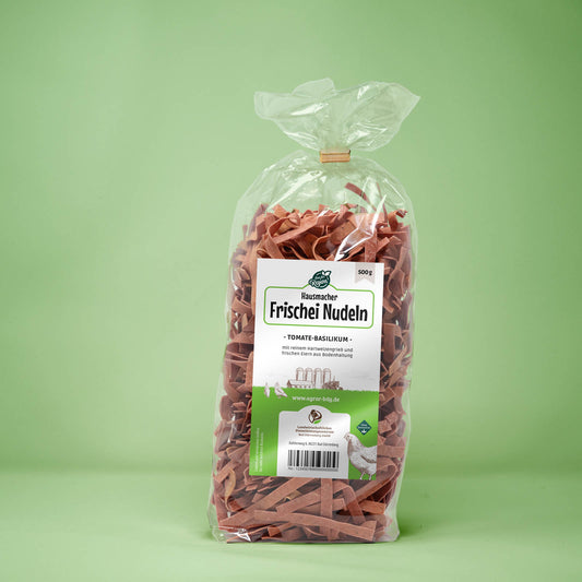 Frontalansicht von Hausmacher Frischei Tomate-Basilikum Nudeln 500 Gramm in einer Plastiktüte mit Etikett.